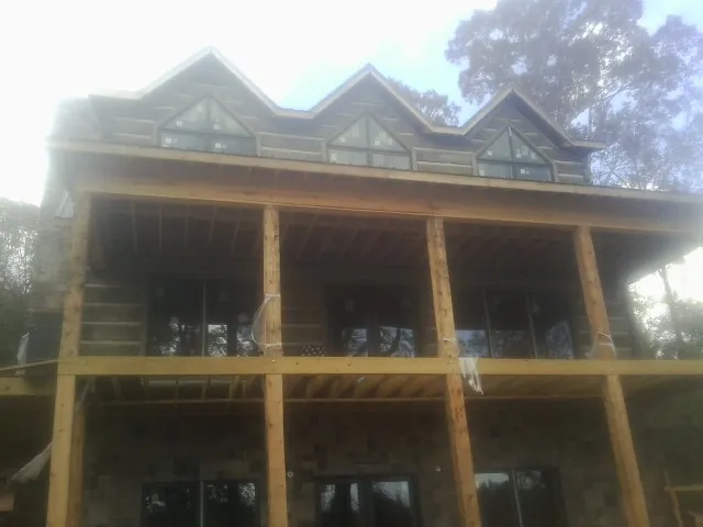 Dormers and porch framing on a large log home under construction — Roof Coating work by our crew in Dillon